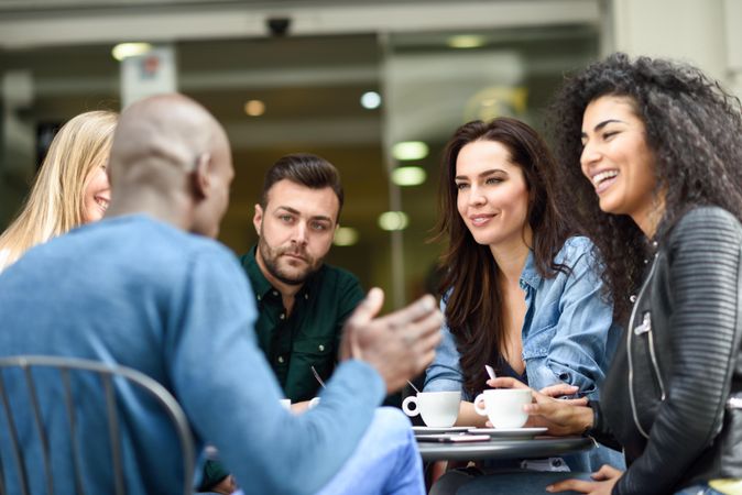 Group of women and men sipping coffee together at outdoor cafe