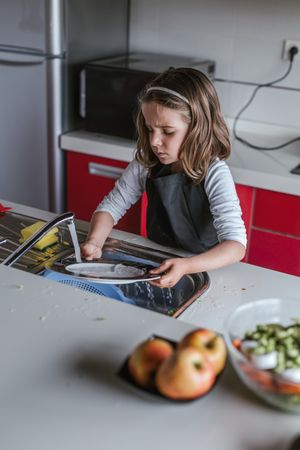 Girl washing dishes in kitchen