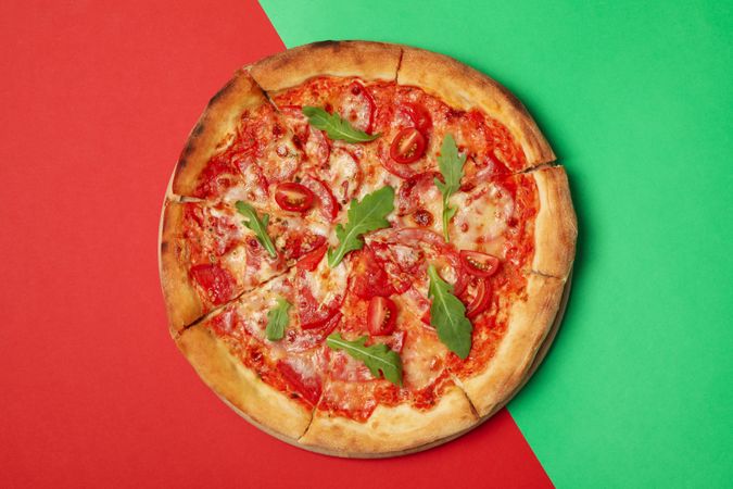 Tasty pizza with tomato on two tone background