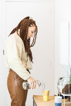 Woman with braids serving water in a glass