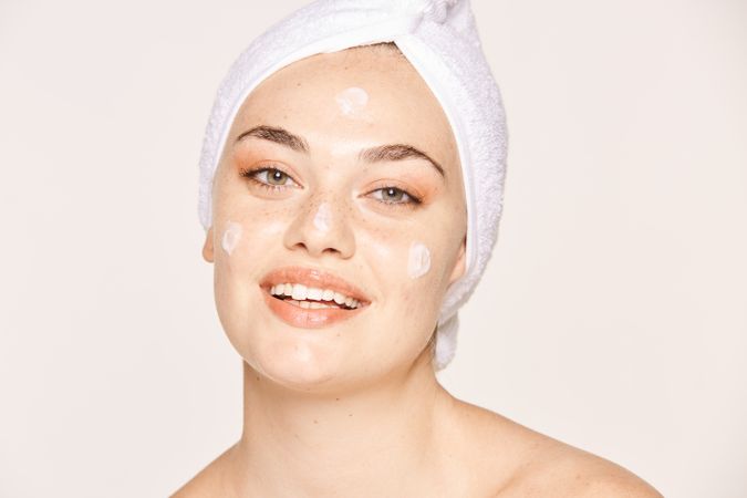 Delighted female with radiant skin applying cream