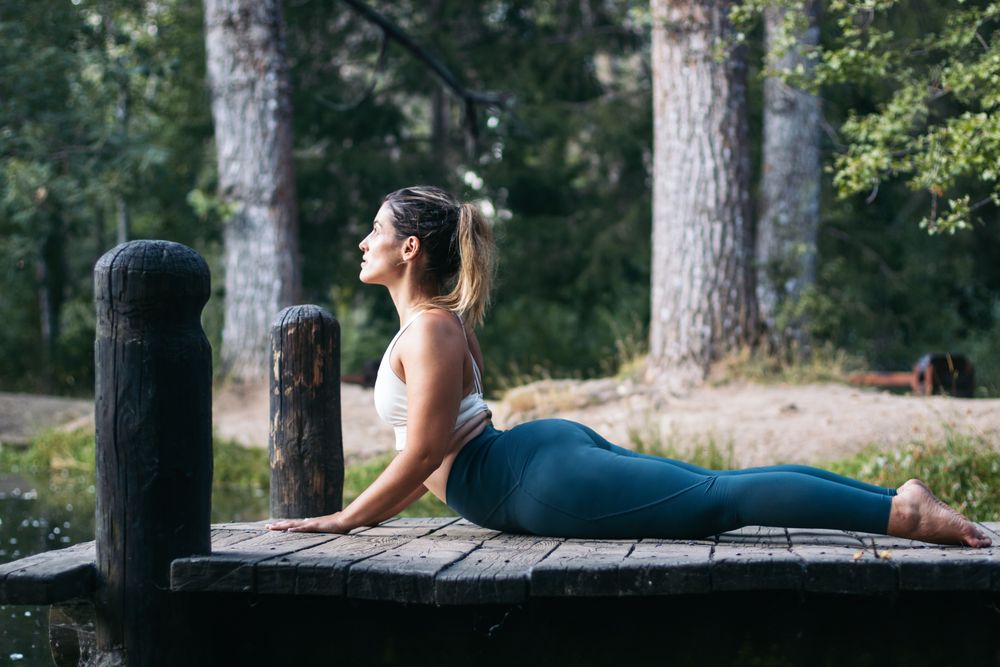 Woman in sportswear doing yoga in nature near a lake
