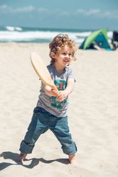 Content boy playing with racket on beach