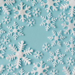 Winter pattern made of different sized snowflakes on blue background