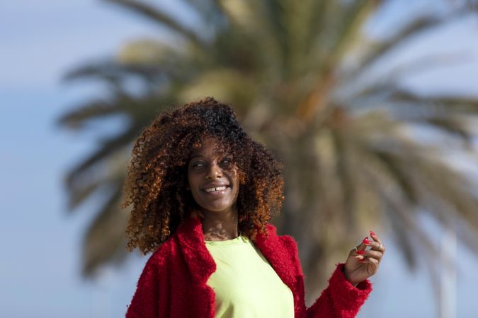 Female with curly hair smiling and looking to her side on sunny day