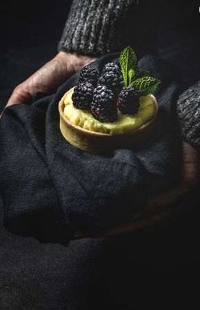 Hand holding a blackberry tartlet
