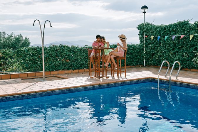 a group of young people having a celebration by the pool on a cloudy summer day
