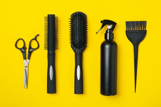 Flat lay with hairdresser accessories on yellow background, top view