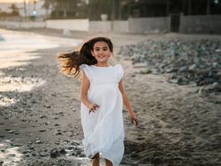 Excited girl running along beach in daylight