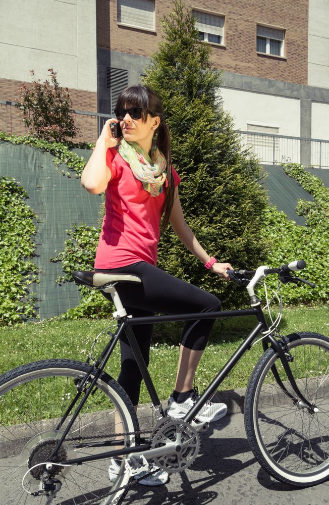 Sportive woman with fixie bike calling by phone