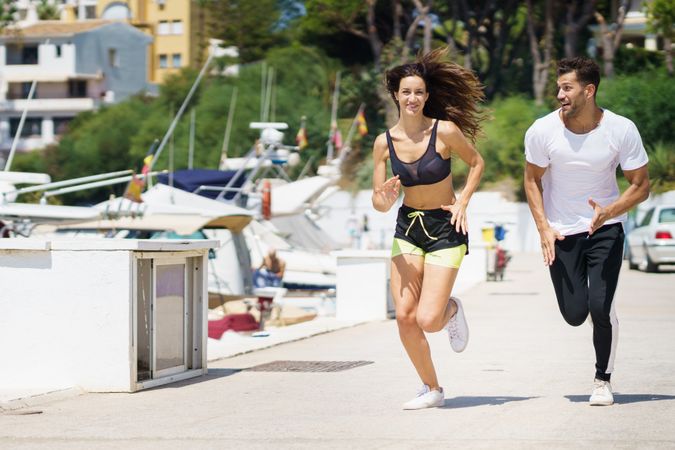 Man and woman jogging together on pier