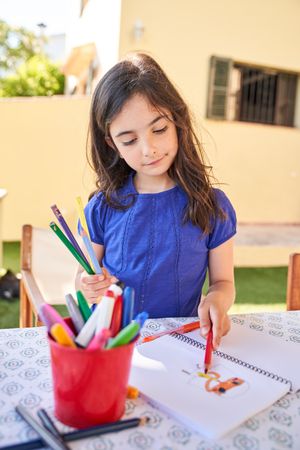 Preteen Hispanic girl coloring picture on paper