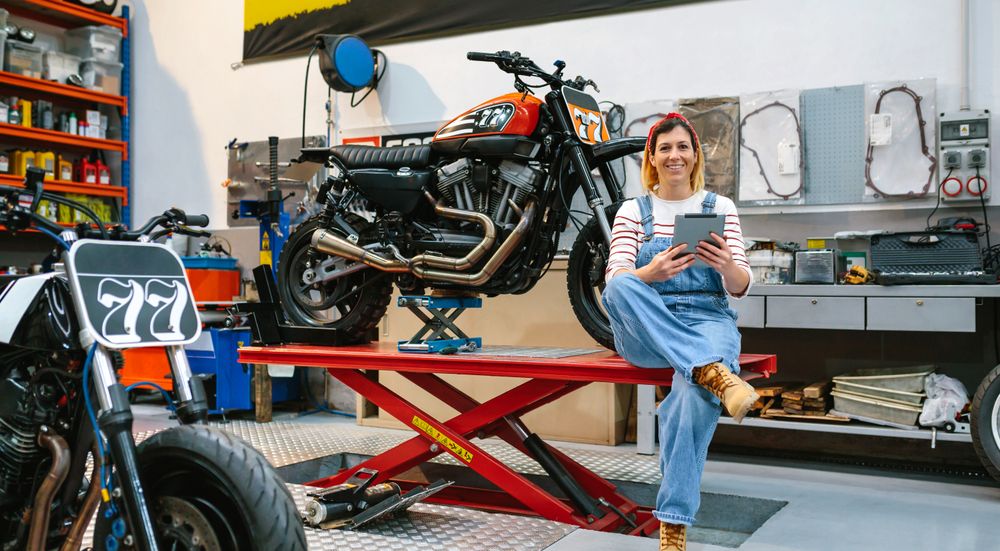 Mechanic woman holding digital tablet sitting over platform