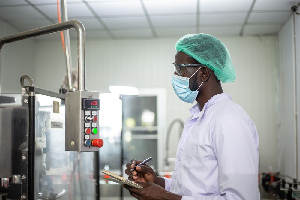 Man in hairnet and facemask taking notes at factory