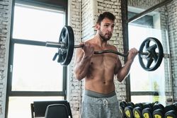 Bearded man exercising with barbell in gym