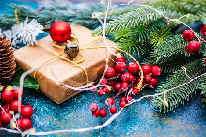 Christmas gift surrounded by fir, berries, bauble and pine cones