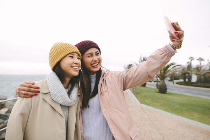 Two young Asian women in winter clothes take funny selfie