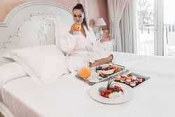 Woman drinking juice during breakfast on bed