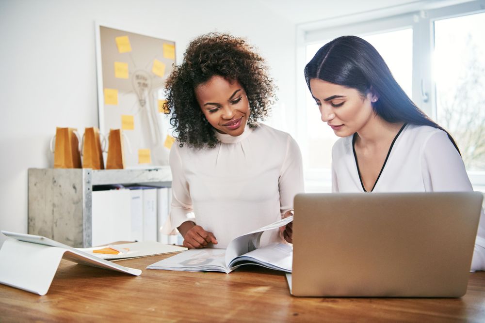 Two female colleagues working together in a bright modern office