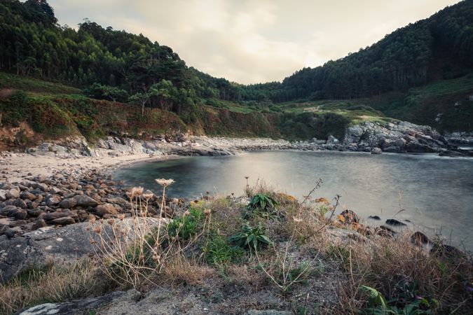 Empty rocked tropical seashore and green forest on mountains
