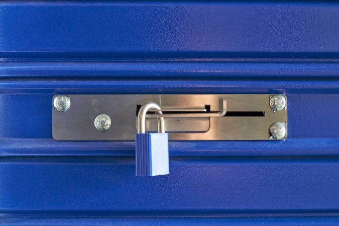 A blue locked lock on a metal barrier in a storeroom