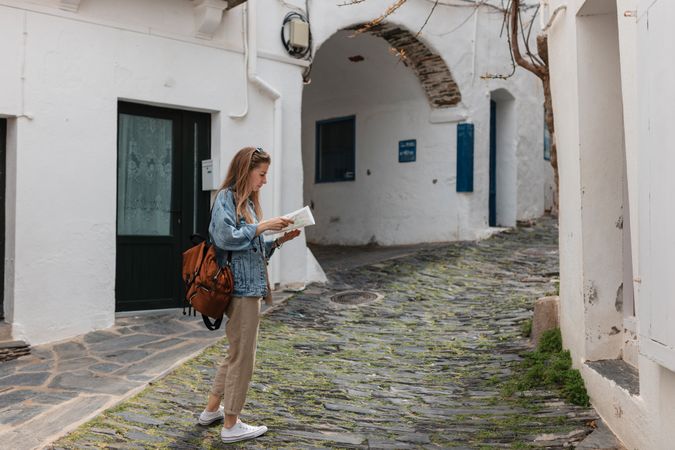 Woman exploring small town with narrow streets and white buildings holding a map
