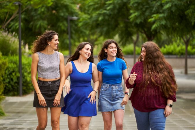 Group of friends talking while walking through a park when it is