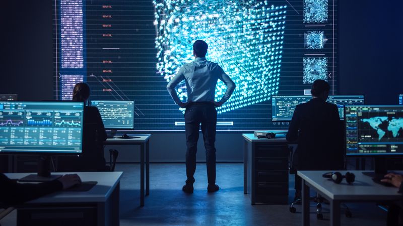 In a Futuristic Control Room, a Diverse Team Analyzes Data on Multiple Screens, Focusing on a Large Digital Display With Intricate Patterns for Strategic Insights and Decision-making.