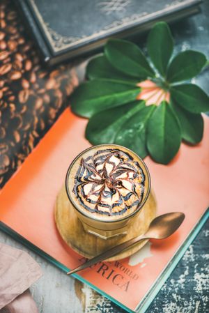 Top view of latte with decorative pattern in chocolate syrup on orange table setting