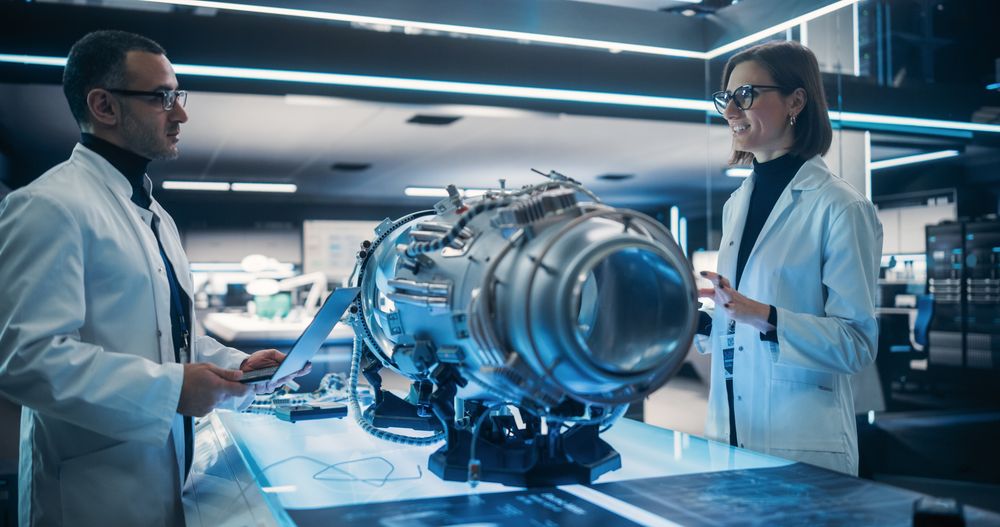 Professional Multicultural Team of Female and Male Engineers Working On Industrial Jet Turbine in a Factory Development Workshop.