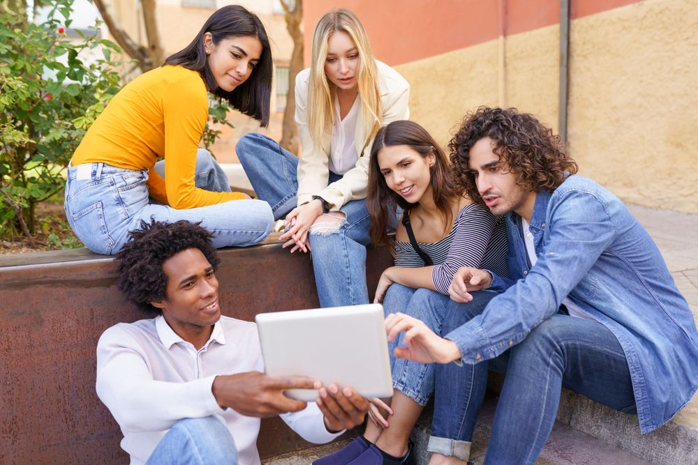 Friends gathered around a digital tablet outside
