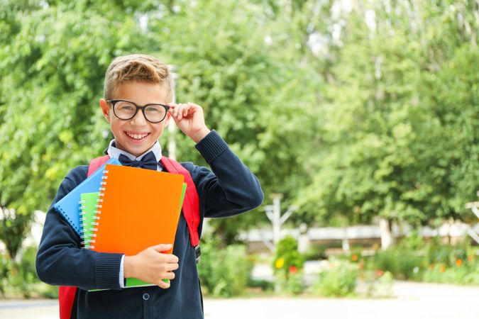Boy in school uniform against greenery background, space for text
