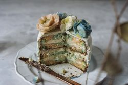 Portion of rainbow cake, filled with chantilly cream, and decorated with buttercream flowers
