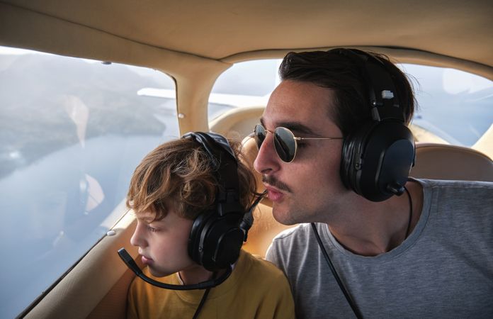Father and son flying in airplane above sea