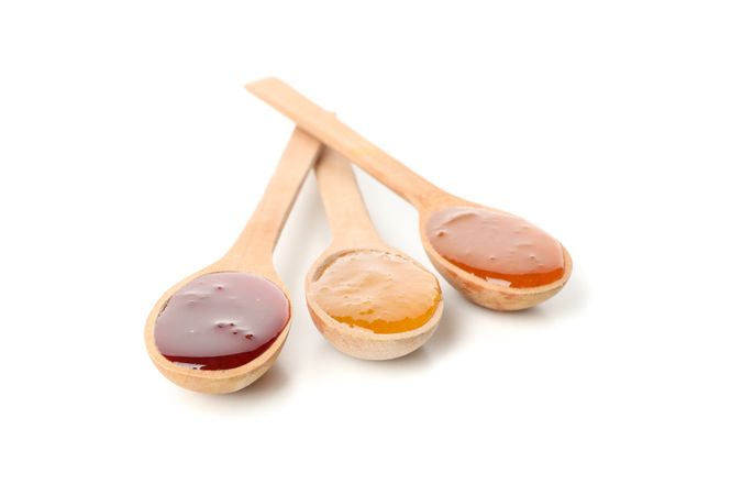 Spoons with jam isolated on plain background