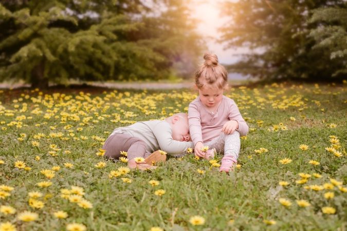 Girl and a baby sitting in yellow flower field