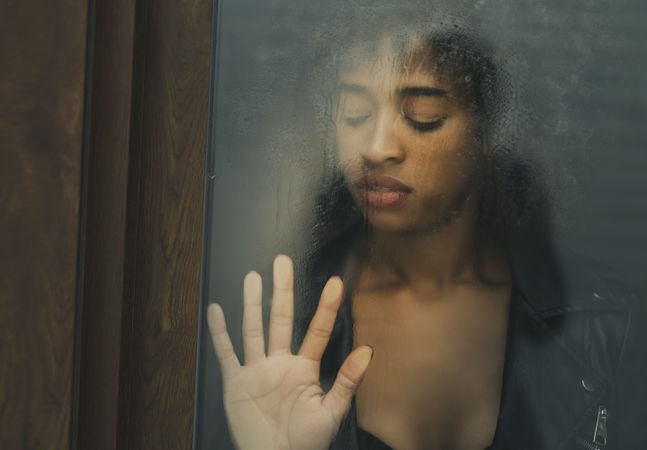 Black female touching wet window