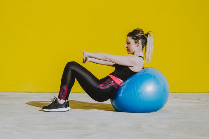 Woman stretching while leaning on ball