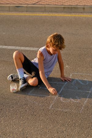 Child drawing with chalk on asphalt