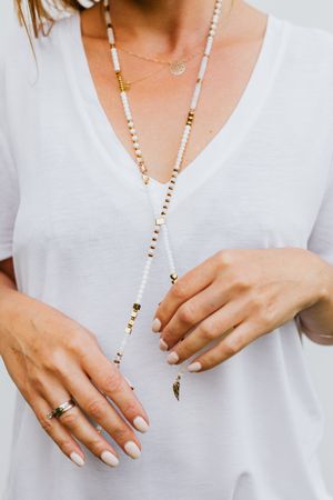 Cropped image of woman in light shirt wearing beaded necklace