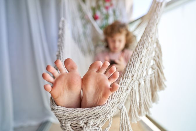 Cute child relaxing in hammock with cellphone