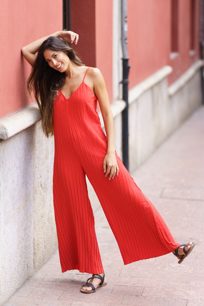 An Elegant Woman in a Stunning Red Jumpsuit is Gracefully Posing Outdoors in Nature