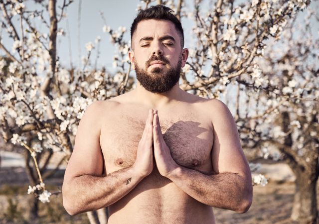 Shirtless man meditating in spring garden