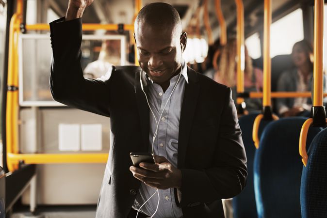 Man in business attire smiling at his phone on public transport