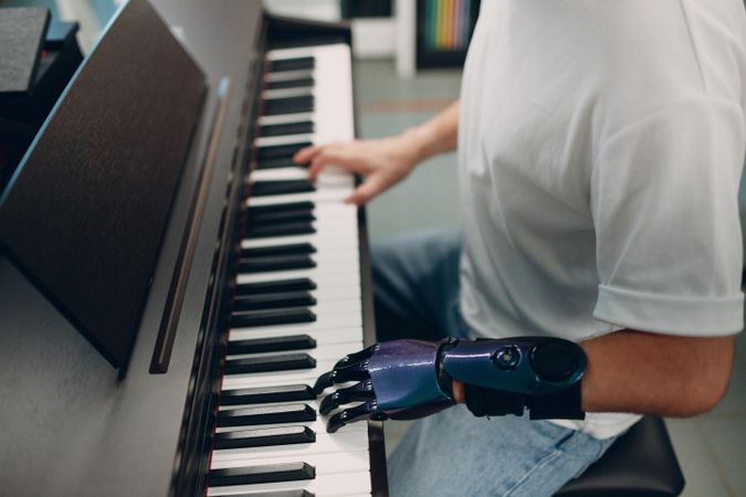 Cropped image of young man playing the piano with his prosthetic hand