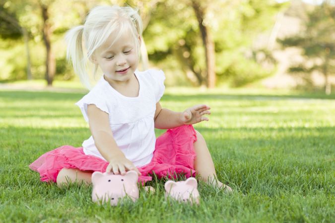 Little Girl Having Fun with Her Piggy Banks Outside