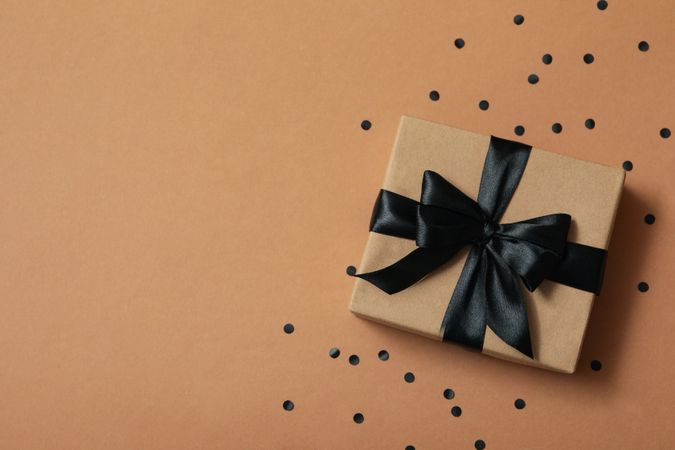 Gift box with dark bow on craft background