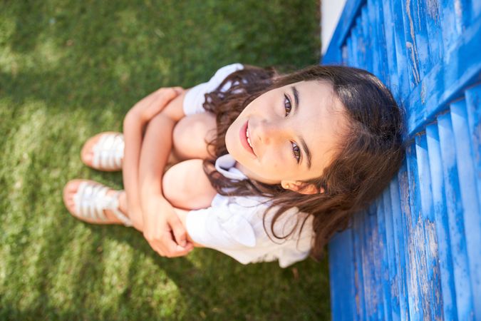Preteen child hugging knees in garden