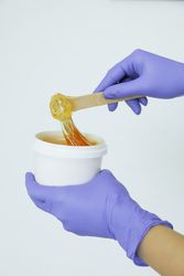Women's hands holding liquid yellow paste for sugaring against, copy space
