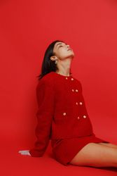 Woman in red skirt suit sitting against red background